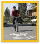 Photo of a bicyclist cycling on a road with a sharrow sign